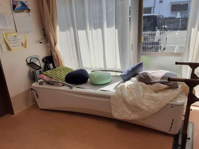 明るい居室の一角 居室 窓辺には日差しが届くベッドがあり、温かみのある空間でリラックスできる様子です。