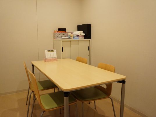 やや横長となっているテーブルには、4つのイスが用意されており、部屋の片隅には物を収納できる棚がある。