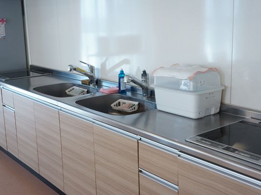 キッチンは2つの水道設備、IHヒーターが設置されており、食器などを入れておく容器も上に置かれている。