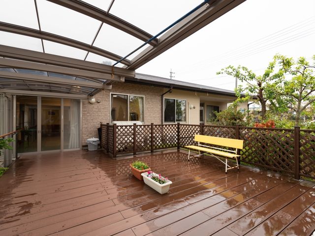 庭付き施設のテラス バルコニー 雨の日でも過ごしやすい、屋根付きのテラス空間。植物に囲まれたベンチは、穏やかなひと時を提供します。