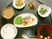サムネイル 施設の写真 黒く丸い配膳盆に小鉢に盛り付けられた食事が並べられている。焼き魚と白飯やお吸い物などの和食の献立である。