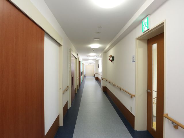 清潔な廊下の様子 廊下 温かみのある照明と清潔な空間が、働くスタッフと訪れる方々を優しく迎えています。壁に飾られた装飾も心癒される一角です。