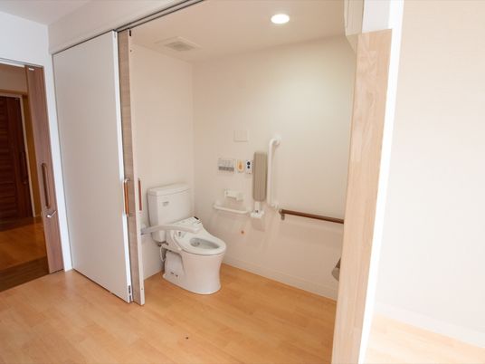 居室内にあるトイレの扉は大きく開くため、車椅子での出入りも楽に行える。手すりや呼び出しボタンも設置されている。