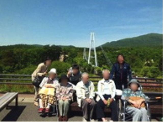 外の椅子に座る人々 旅行 広々とした屋外スペースで、訪れる人々が和やかに過ごしています。自然豊かな背景が、明るい雰囲気を醸し出しています。