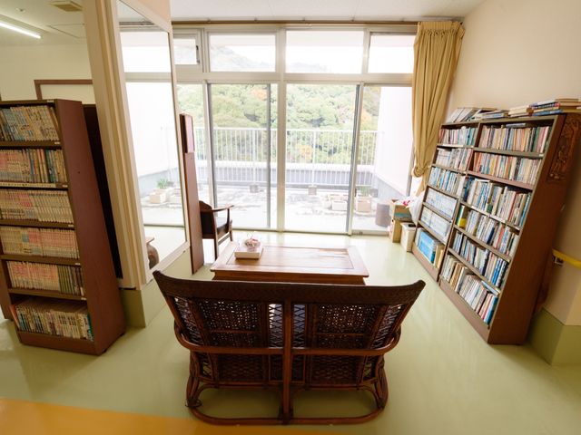 明るい読書スペース 休憩コーナー ゆったりとした椅子と読書用のテーブルが用意されており、大きな窓から自然光が差し込む落ち着いたラウンジです。