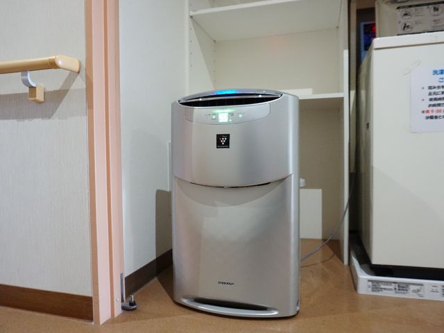 清潔な空気清浄機と手すり 共有スペース 手すりが備わった空間に、高性能な空気清浄機が置かれており、快適な室内環境づくりに役立っています。