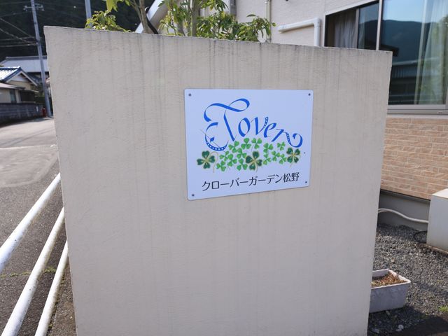 壁に掲示された看板 看板 優しい色合いのロゴが印象的な看板が、施設の顔として迎えてくれます。心温まる出迎えに、きっとあなたも笑顔になるでしょう。