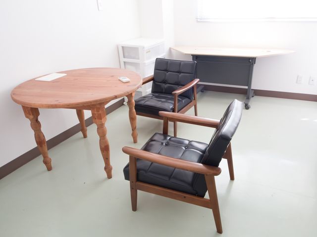 快適な居室の一角 休憩スペース 清潔感があり、明るい居室です。木製のテーブルと快適な椅子が配置され、くつろぎの時間を過ごせる空間となっています。