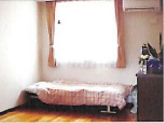 落ち着いた色調の居室 居室 床は暖かみのある木目調で、ベッド隣には小物を置けるスペースもございます。ゆとりを持って快適にお過ごしいただける空間です。