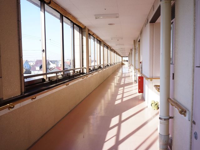 明るい廊下の長い視界 廊下 陽光が差し込む廊下は広々としており、日々の移動も快適に行えそうです。また、壁面に手すりが設置されていて、安全に配慮されています。