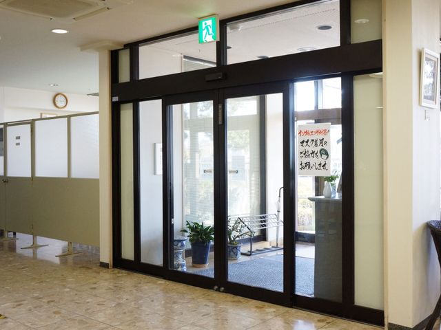 玄関の自動ドア風景 玄関 ゆとりあるエントランスは、出入りの便を考えた自動ドアで、訪れる皆様を温かく迎え入れます。安全かつスムーズな移動が可能です。