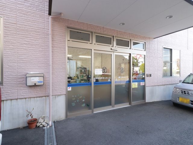 ピンクの壁のエントランス 玄関 ガラス扉の透明感のあふれるエントランスは、温かみのある外観を演出しており、日常の活動に安心を与える設計です。