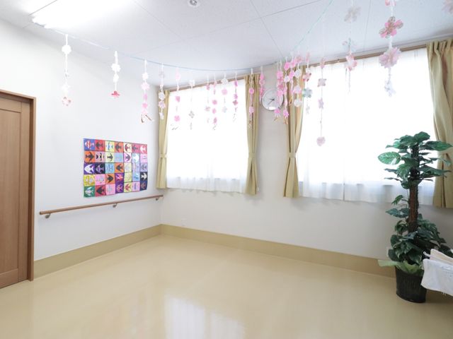 花飾りのある明るい部屋 廊下 ゆとりのある空間に季節の装飾が心温まり、日々の憩いの場として利用されています。美しい手作りの壁画も設置され、創造性を刺激する環境が整えられています。