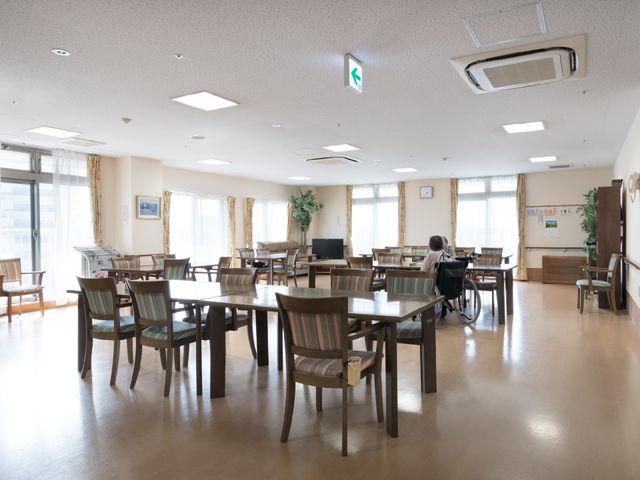 広々としたダイニングルーム 食堂 ゆとりあるダイニングルームで、一人の方がリラックスしながら過ごされています。適度なプライバシーが守られた設計です。
