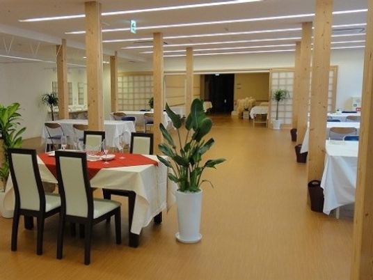 白いテーブルクロスや所々に置かれている観葉植物がお洒落な雰囲気を出している食堂である。多くの構造柱が付けられている。