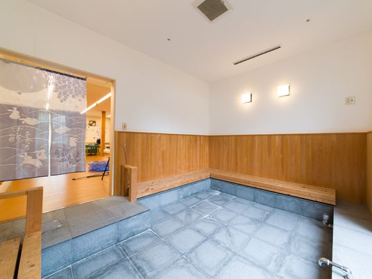 お風呂場は石畳の落ち着いたデザインが特徴である。木目の表れた木材でできた長椅子も風情があふれている。