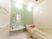 白とグリーンの清潔感のある浴室。浴槽には高さ調節付の手すりが設置されている。壁にも手すりとナースコールが付いている。