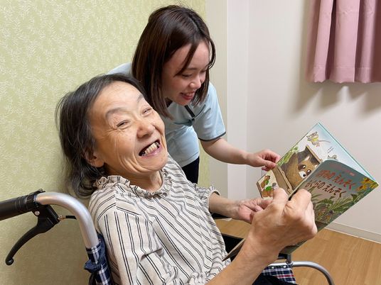 笑顔で読書する高齢者と職員