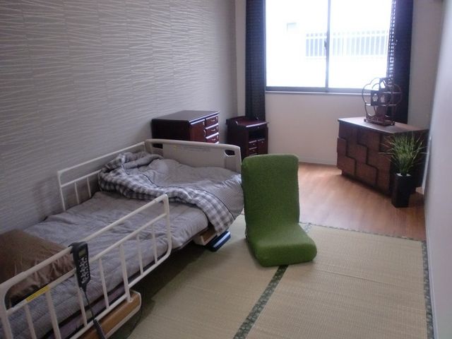 和室調の居室風景 居室4 落ち着いた色合いの居室です。ベッド周辺に必要なものが整っており、居心地の良い空間を提供しています。
