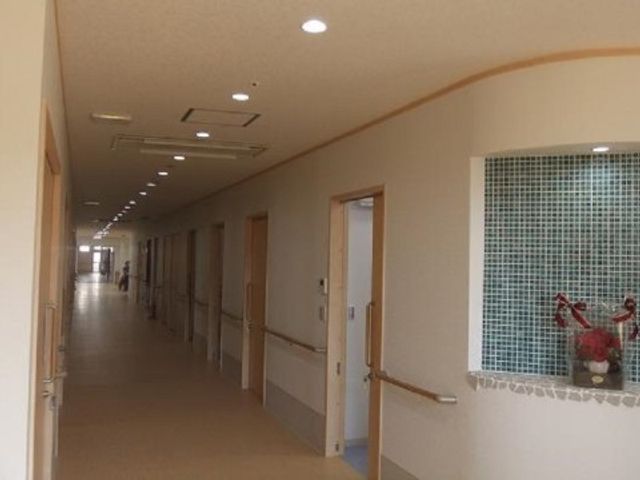 廊下の明るい雰囲気 廊下 幅広で明るい廊下は、ゆったりと動きやすく設計されています。右側には個室の入り口が並び、左手には装飾が施された小窓があります。