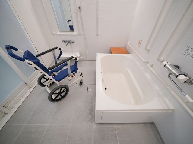 バリアフリー浴室と車椅子 浴室 車椅子用のスペースが確保された清潔感ある浴室です。安全に配慮された手すりや座面も完備しておりますので、安心してご利用いただけます。