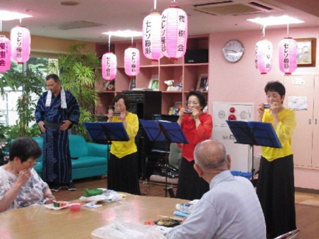 楽器演奏する集いの様子 レクリエーション 明るく温かな雰囲気の中で、楽器を演奏する活動が行われ、笑顔で耳を傾ける方々がいらっしゃいます。