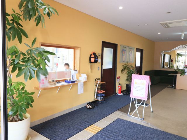 暖かい雰囲気の入り口 受付 笑顔で迎える受付と、くつろぎのソファが設置された明るいエントランスです。暖かい印象の空間で、来訪者とのコミュニケーションもとれる場所です。