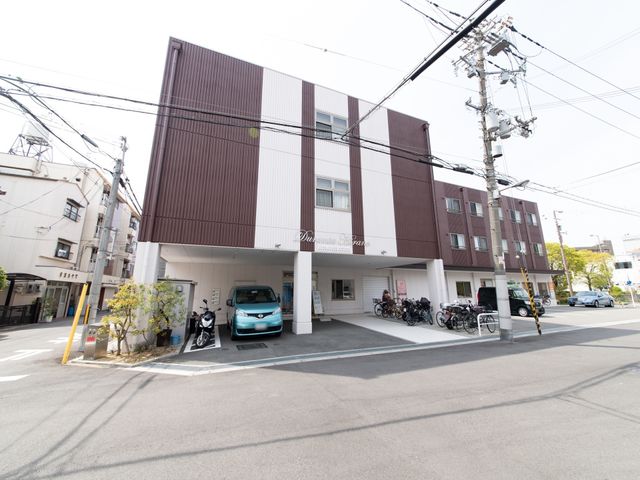 茶色の建物の外観 外観 都市の一角に佇む清潔感のある建物です。広々とした駐車スペースが確保されており、アクセスも便利です。