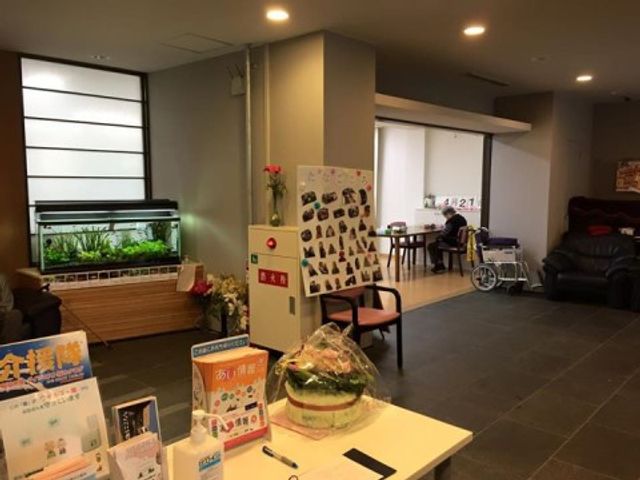 共有スペースと掲示物 ロビー ゆったりとした共有スペースには、植物が飾られ落ち着いた雰囲気が漂っており、車椅子をご使用の方もくつろいでいらっしゃいます。