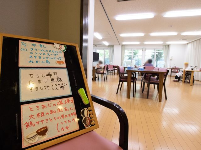 掲示板と食堂の風景 食堂 ゆったりとした食堂で、利用者の皆さまが食事を楽しみながらコミュニケーションを取る姿が見受けられます。職員としての新たな一日がここで始まります。