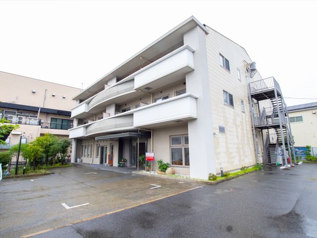 白い外壁の建物エントランス 外観 清潔感のある白い外壁のエントランスは、明るい印象を与え、訪れる方々を迎え入れます。ゆったりとしたスペースのある出入口は、バリアフリーにも配慮されています。