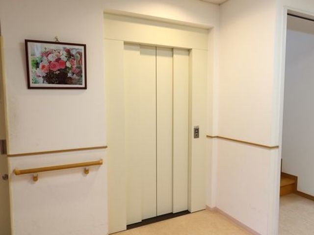 清潔感のあるエレベーター前 エレベーターホール 壁には花の絵が飾られた、清潔で明るいエレベーターホールです。手すり付きで安全に配慮されております。