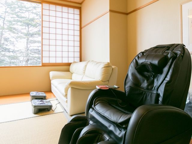 明るい和室の居室 マッサージチェア 落ち着いた雰囲気の和室には、リラックスできるマッサージチェアが備えられ、くつろぎの時間をサポートします。窓からは自然光が差し込み、穏やかな空間を演出しています。