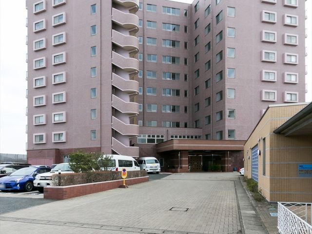 ピンク色の高層建築外観 外観 モダンな建築の高層建物が立地し、入口が広く開放的です。広々としたアクセスは、訪れる人々を優しく迎え入れる印象を与えます。