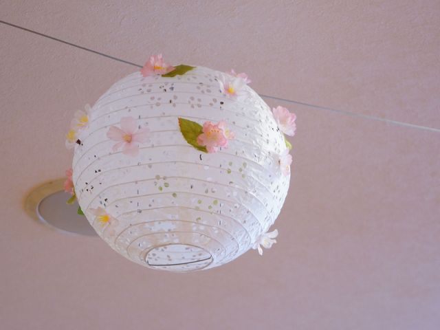 桜の飾り付けられた照明器具 飾り 穏やかな光を放つ照明には桜の花が添えられ、暖かい雰囲気の空間を演出しています。リラックスタイムを大切にする環境です。