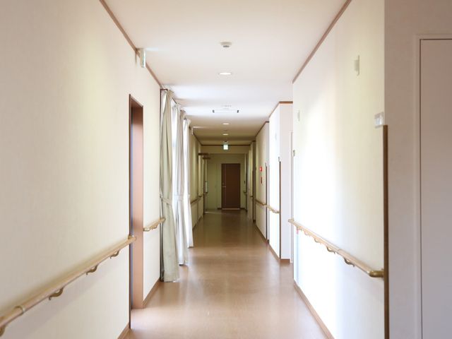 明るい廊下の風景 廊下 手すり付きの廊下は、明るく開放的な空間を提供しており、ご利用者の安全な移動を支えています。