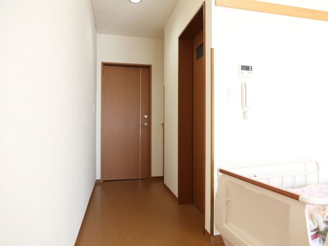 明るい廊下と部屋の入口 居室 落ち着いた色合いの廊下には、しっかりと手すりが設置されています。安全に配慮された空間でお仕事をしてみませんか。