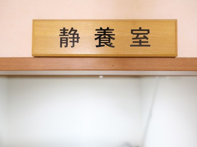 看板の木製プレート 静養室 明朝体で「再診受付」と書かれた木製の掲示板が壁にしっかり取り付けられています。美しい文字が、日々の業務の流れを支えています。