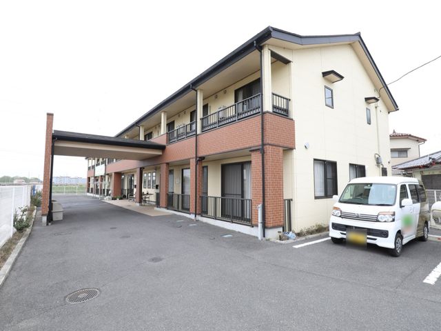 明るい外観のケアハウス 駐車場 広々とした敷地に建つ、落ち着いた色合いの建物です。アクセスもよく、快適な職場環境が期待できます。