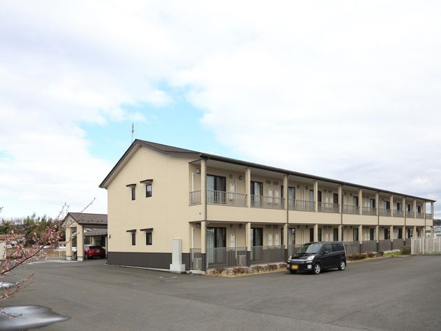 清潔感のある二階建て建物 外観 広々とした駐車場が完備された落ち着いた色合いの二階建て施設です。ゆとりある環境でのお仕事をお考えの方に適しています。