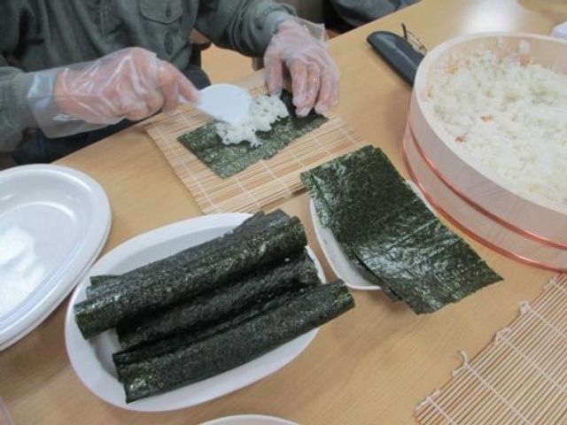 手作り寿司の活動 食イベント 手際よくお寿司を作る参加者の姿が見て取れます。共同で料理を楽しむ様子は、チームワークを大切にする就業環境の一端を垣間見ることができます。