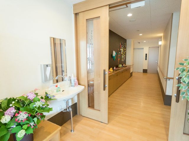 明るい廊下と洗面所 廊下 手入れが行き届いた廊下は、ゆったりとしたスペースで明るい雰囲気です。壁に飾られた装飾品が暖かな印象を与え、訪れる方々を心地よく迎えます。