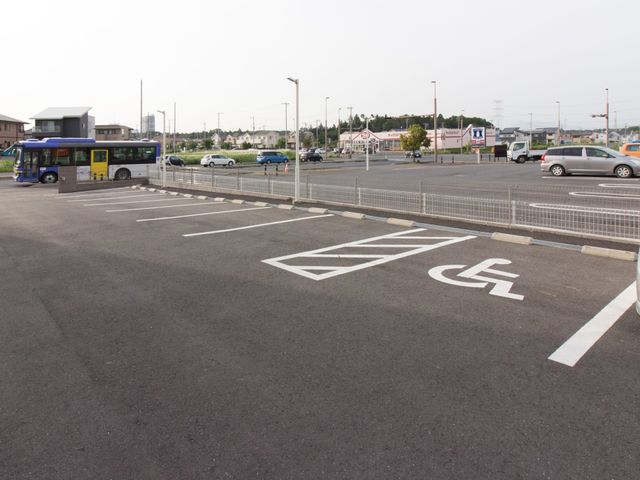 バス停付近の駐車スペース 駐車場 アクセスしやすい立地に位置する快適なエントランスです。バリアフリー対応の駐車スペースも完備され、利便性が高い環境を備えています。