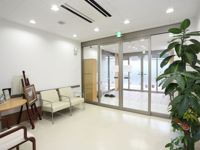 明るく広い待合室 エントランス ゆったりした空間のエントランスで、足元には観葉植物が置かれ、温かみのある雰囲気です。過ごしやすい待合いの場所が整えられています。