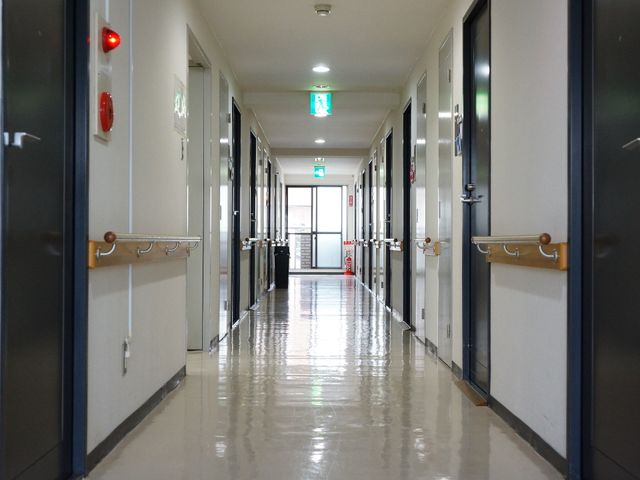 清潔な施設の廊下 廊下 床がピカピカに磨かれ、手すりが廊下の両側に設けられています。働く上で清潔さや安全面が配慮された環境が整っています。