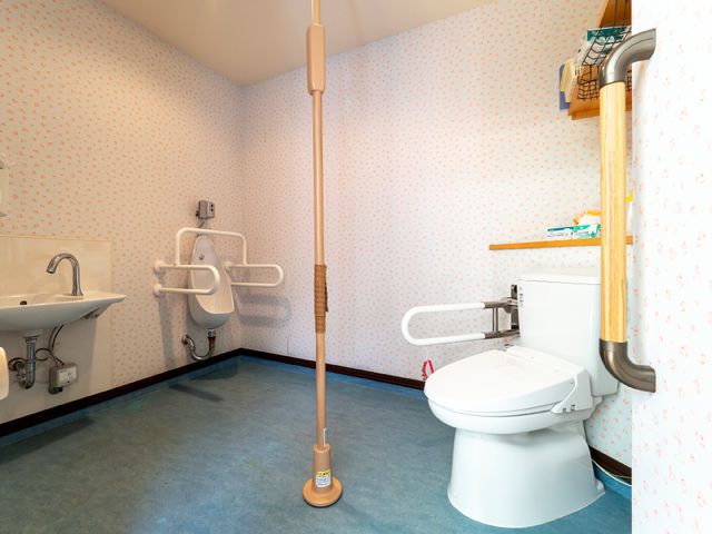 手すり付き清潔なトイレ トイレ 安全なサポートが充実した使いやすいトイレです。手すりや床の色がきれいに保たれており、清潔感があります。