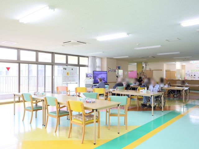 多機能空間の居室 食堂 ゆったりとした座席の並ぶ多目的室です。日差しが差し込む明るい空間で、利用者の方々がくつろぎの時間を過ごしています。