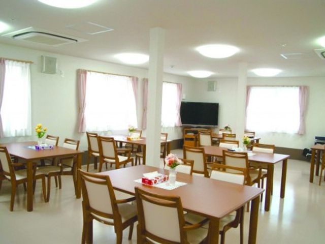 明るい共用食堂 リビング2 広々とした食堂は天井が高く、開放的な空間が広がっています。デイサービス利用者が食事や交流を楽しむ場所です。