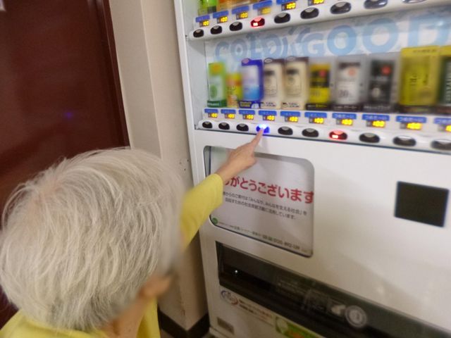 自動販売機を操作する利用者 ダイニングルーム 明るく落ち着いた雰囲気の中で、自動販売機を利用しているご高齢の方がいらっしゃいます。