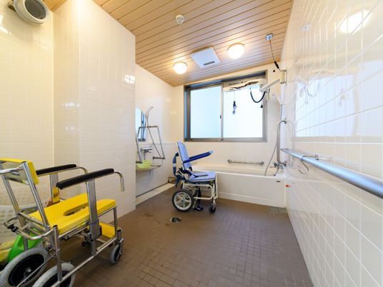 窓から明るい光が差し込む広々とした浴室。車椅子をご利用の方も快適に入浴することができるリフト式の浴槽が設置されている。